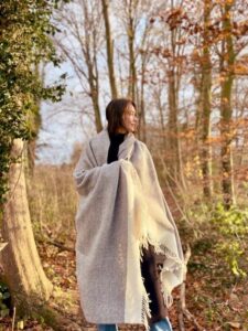 A woman standing in the woods with a blanket.